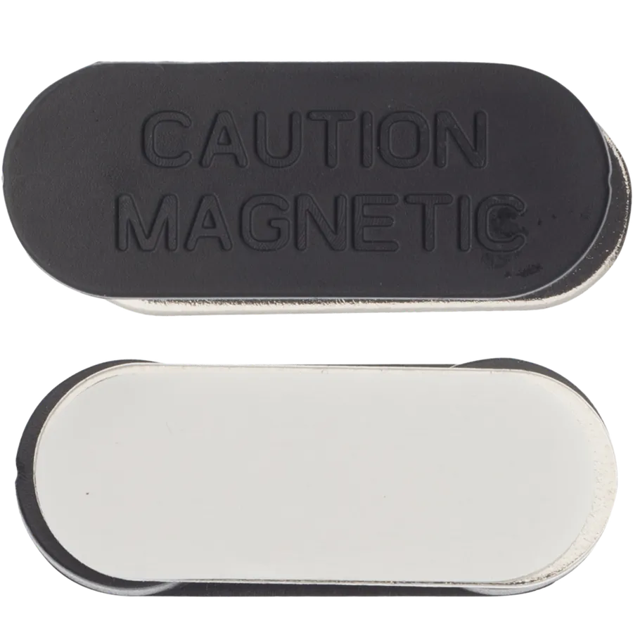 Musta soikea magneetti itseliimautuvalla pohjalla, kuvassa molemmat puolet ja merkintä CAUTION MAGNETIC.