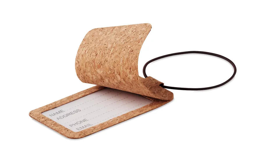 Beige korkkinen matkalaukkutägi, jossa kuminauhalenkki ja nimikortti läpän alla.