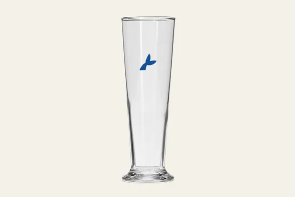 Korkea jalallinen kirkas lasi, jonka kyljessä sininen logopainatus.
