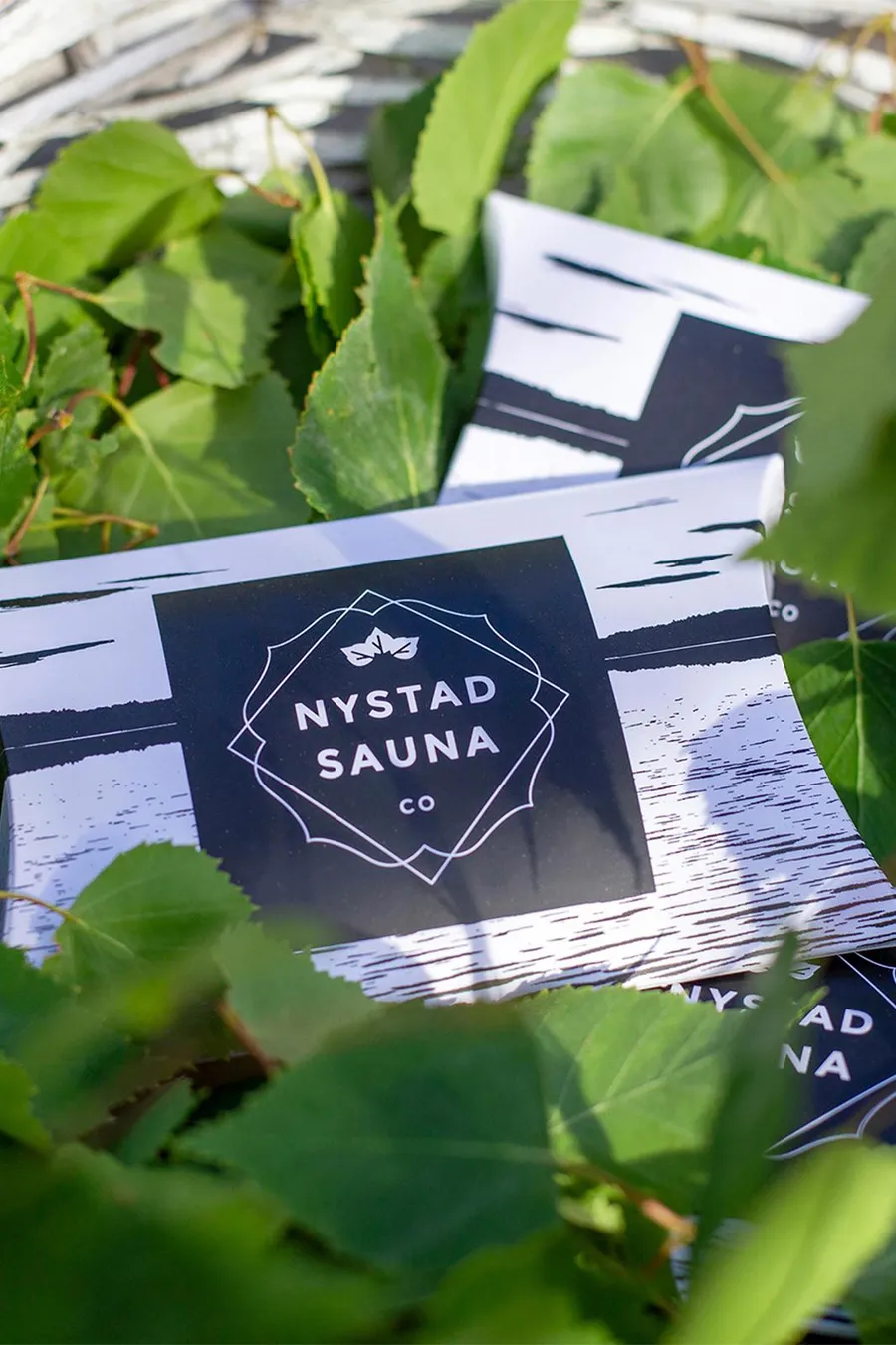 Valkoinen löylytuoksupakkaus, jossa näkyy tumma painatus ja Nystad Sauna -logo.