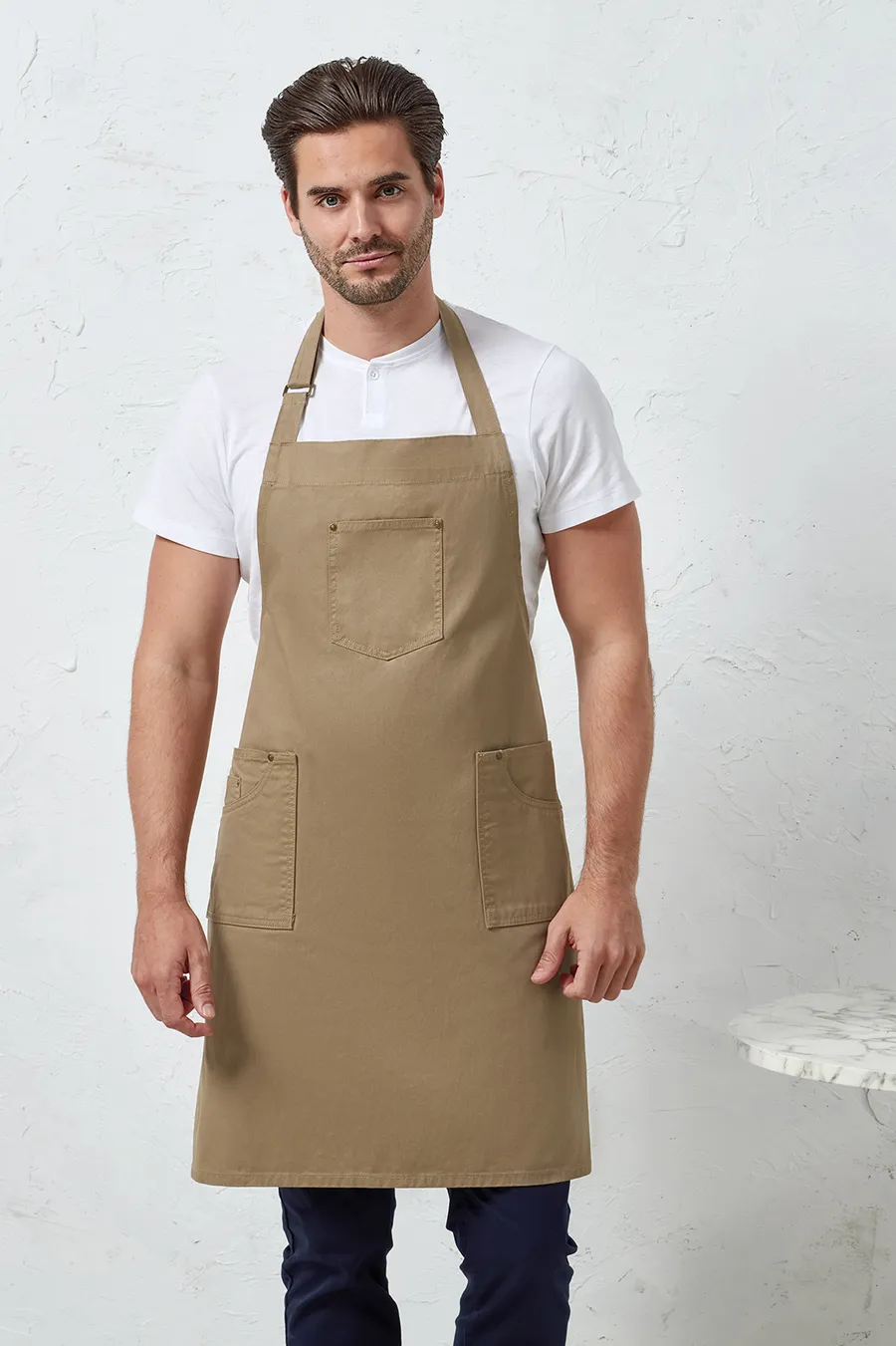 Beige Chino-tyylinen essu kolmella taskulla ja säädettävällä niskanauhalla.