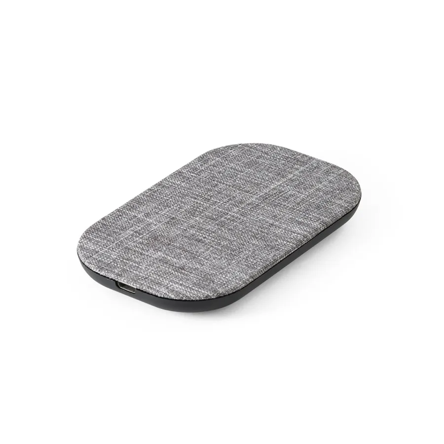 Harmaa soikea langaton laturi, jonka yläpinta on kangasmaista materiaalia ja reunat mustat.