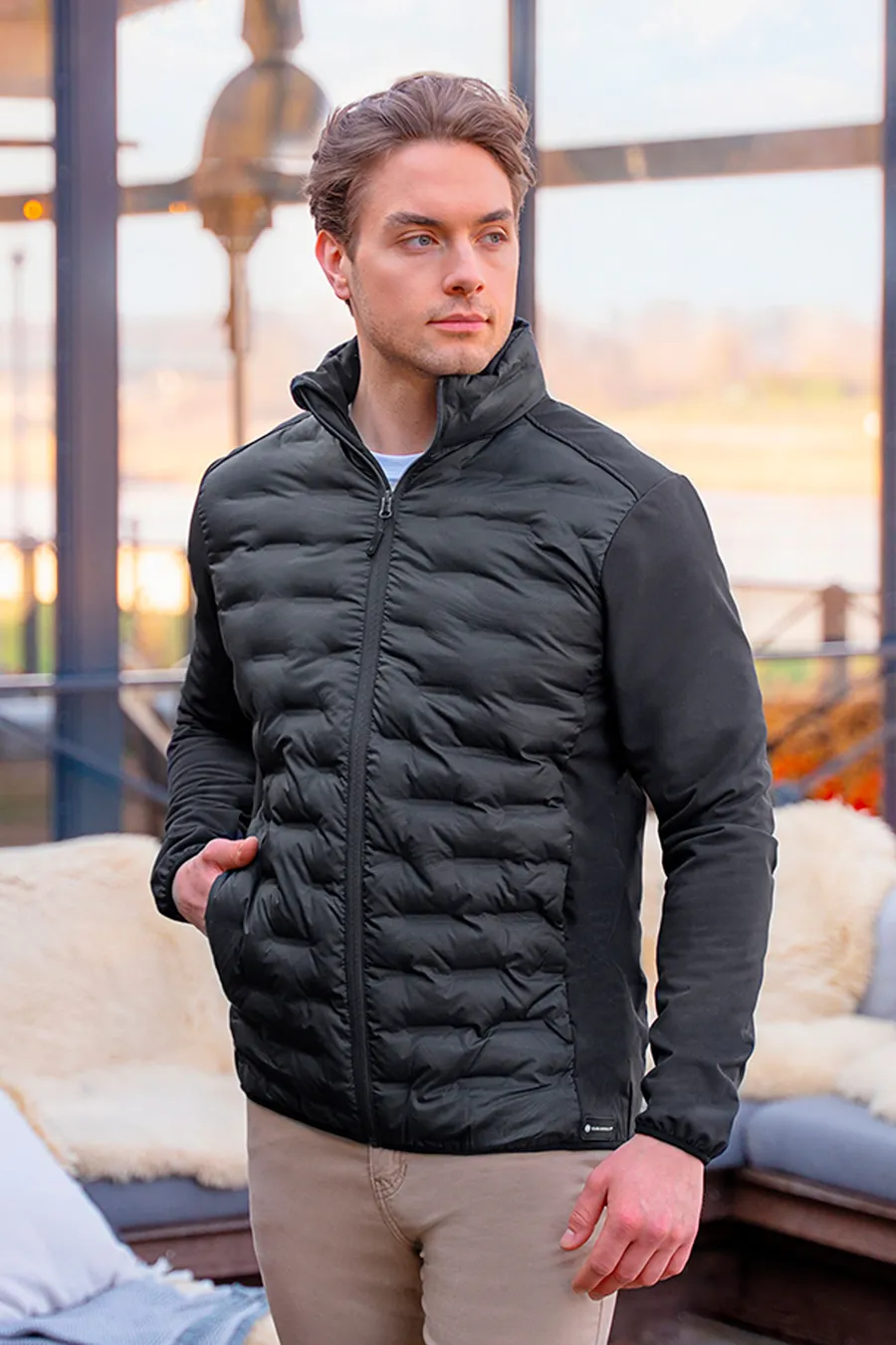 Musta Outdoor-Pro hybriditakki, jossa tikattu etukappale, joustavat hihat ja vetoketjutaskut.