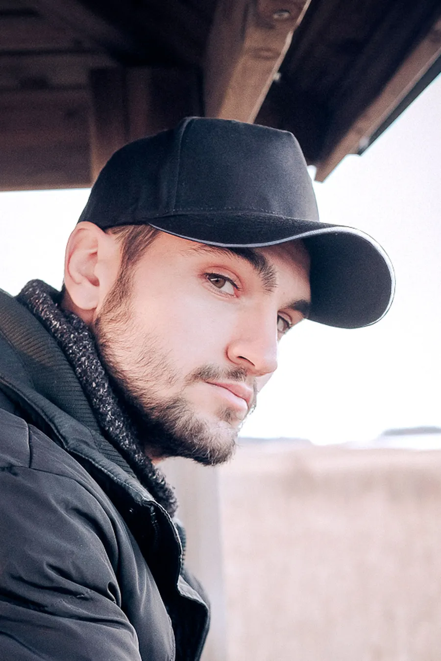 Musta 5-paneelinen snapback-lippalakki, jonka lipan reunassa on vaalea nauha.