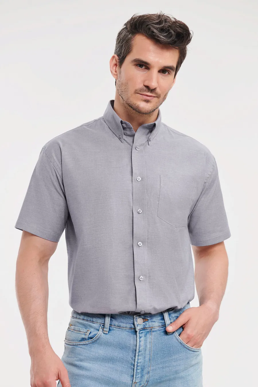 Mies yllään harmaa lyhythihainen Oxford-paita, jossa button-down-kaulus ja rintatasku.