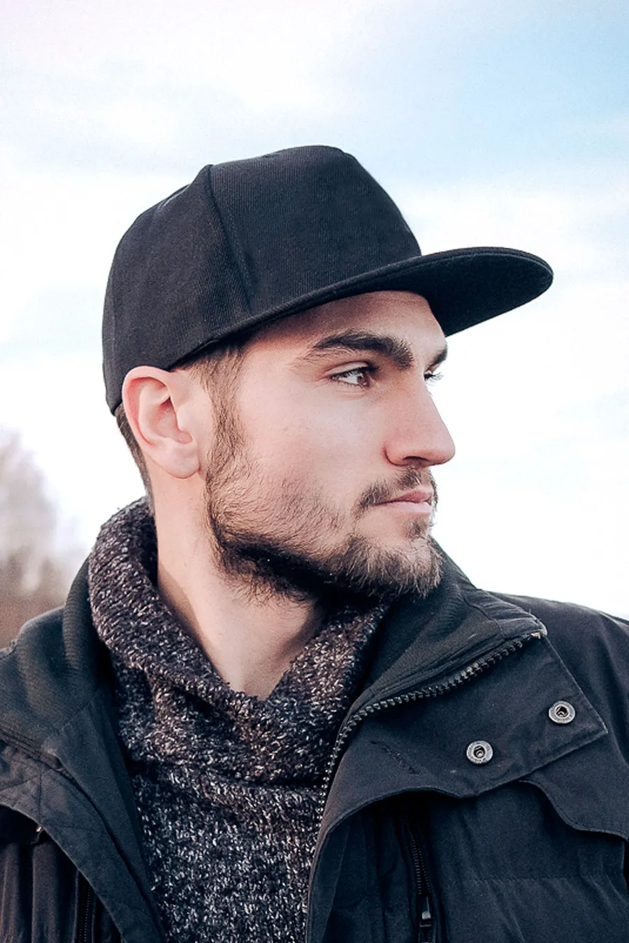 Musta 5-paneelinen snapback-lippalakki suoralla lipalla miehen päässä.