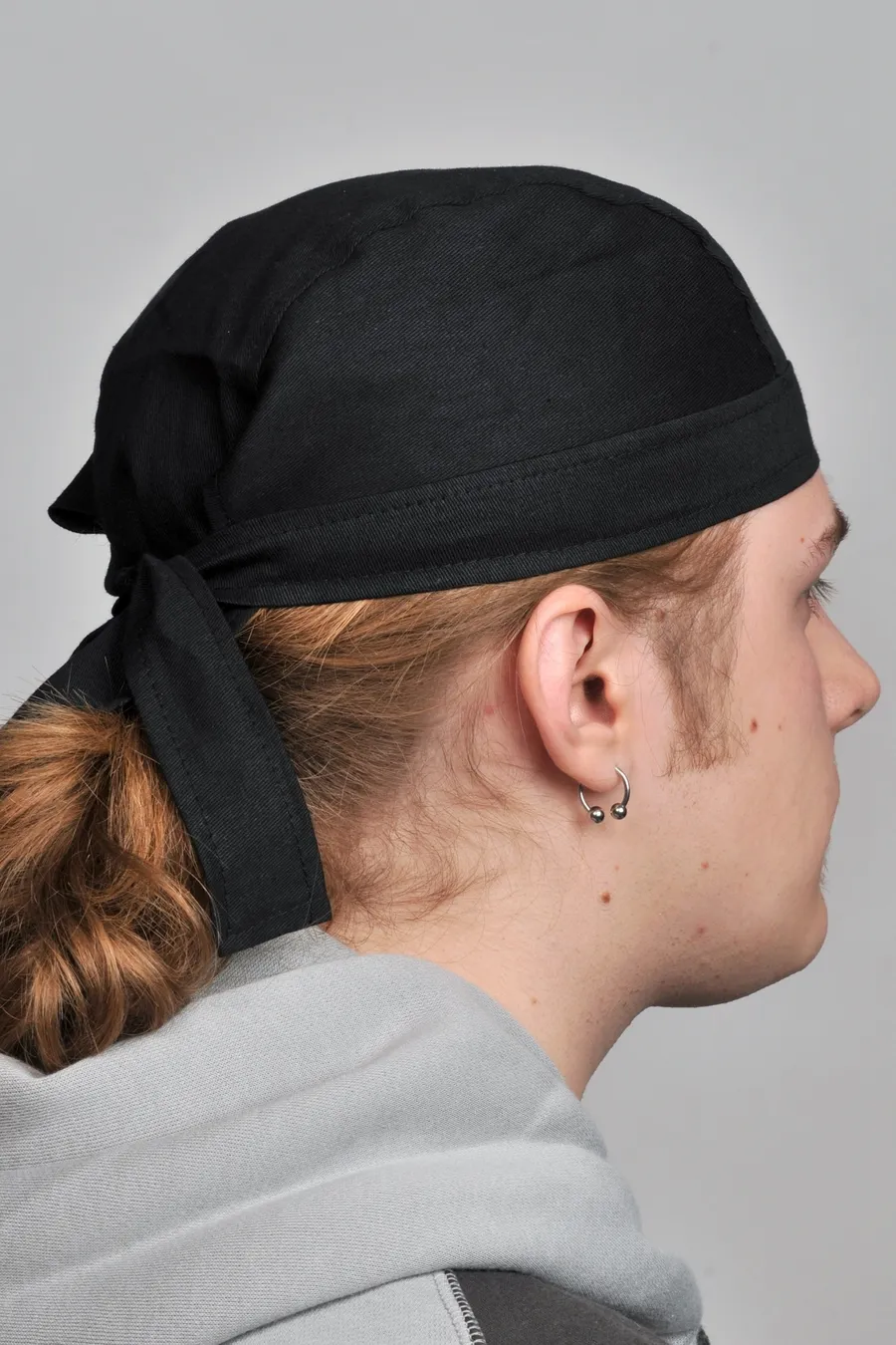 Musta puuvillabandana päähän puettuna, solmittu niskan taakse.