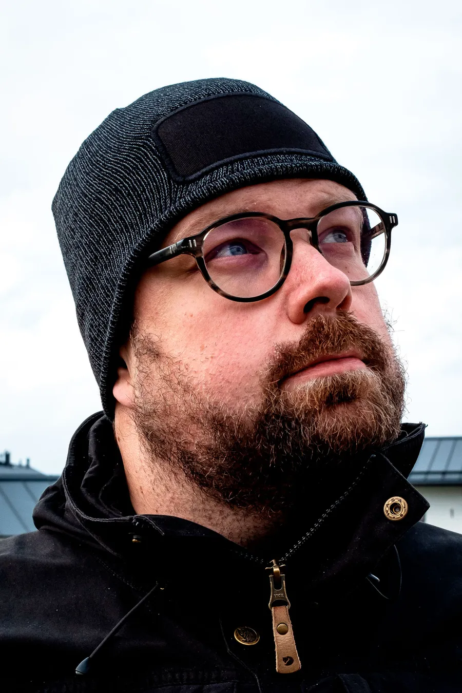 Musta heijastava pipo päässä, edessä painettava tumma kangasmerkki.
