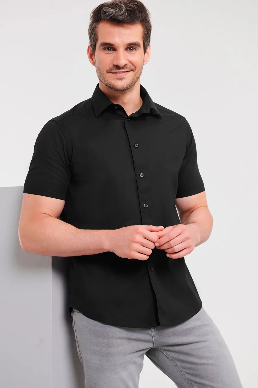 Musta lyhythihainen slim-fit-kauluspaita miehen päällä.