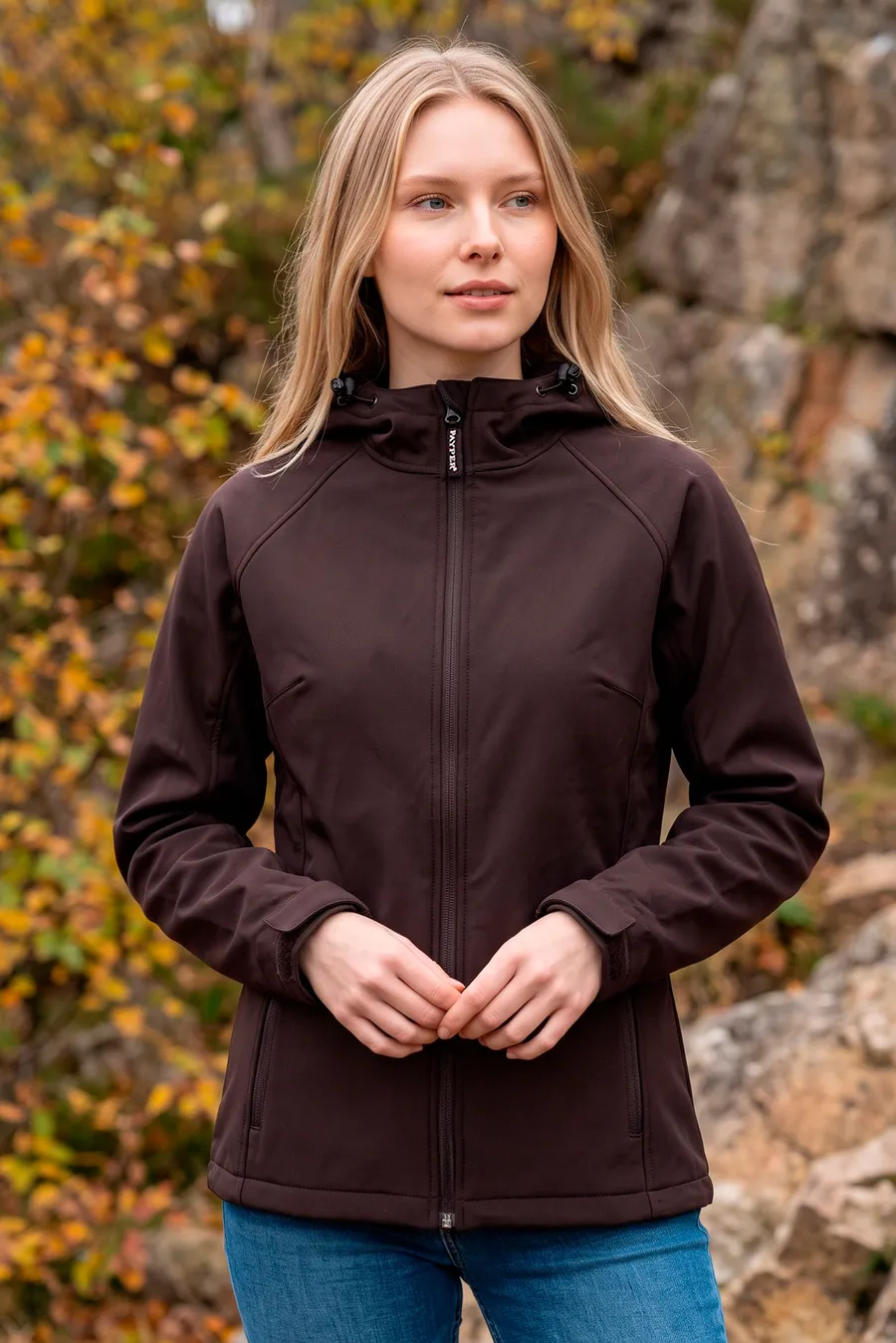 Nainen yllään huppupäinen naisten softshell-takki, jossa vetoketjullinen etuosa ja kaksi vetoketjutaskua.