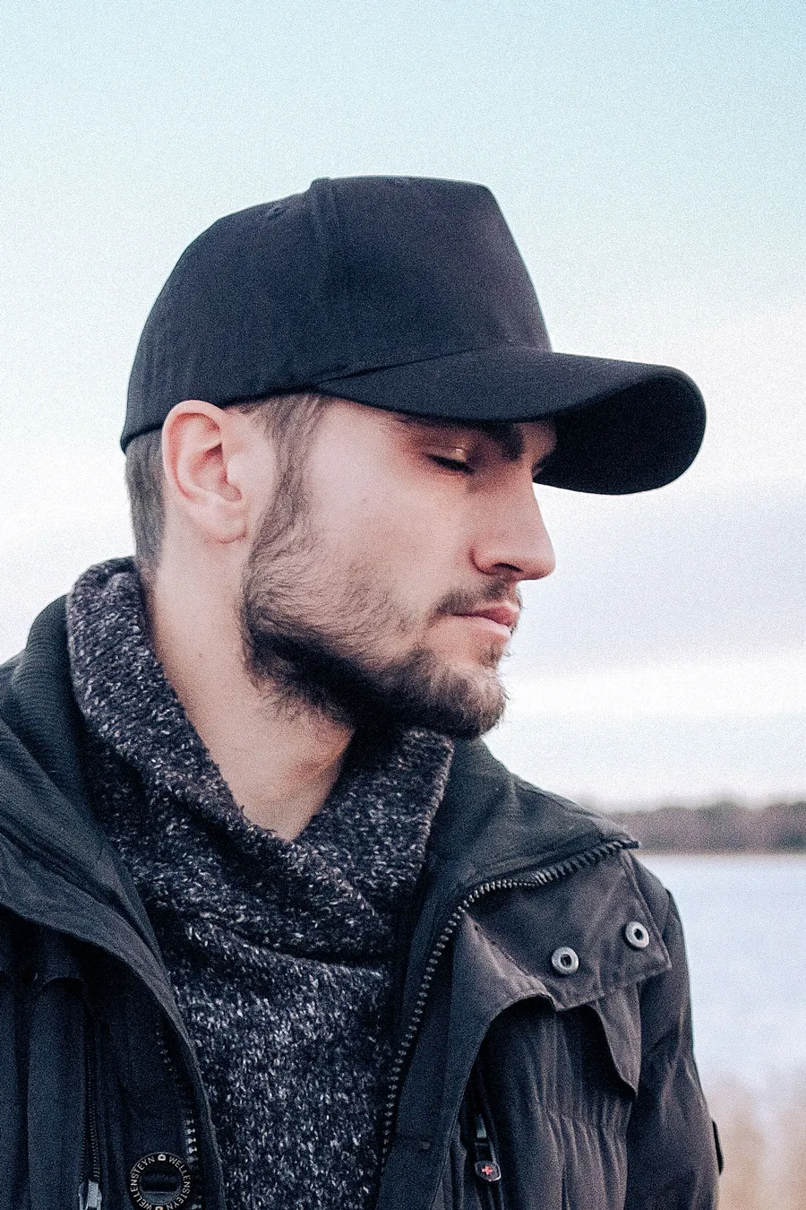 Mustaa 5-paneelista snapback-lippalakkia päässään pitävä mies ulkona.