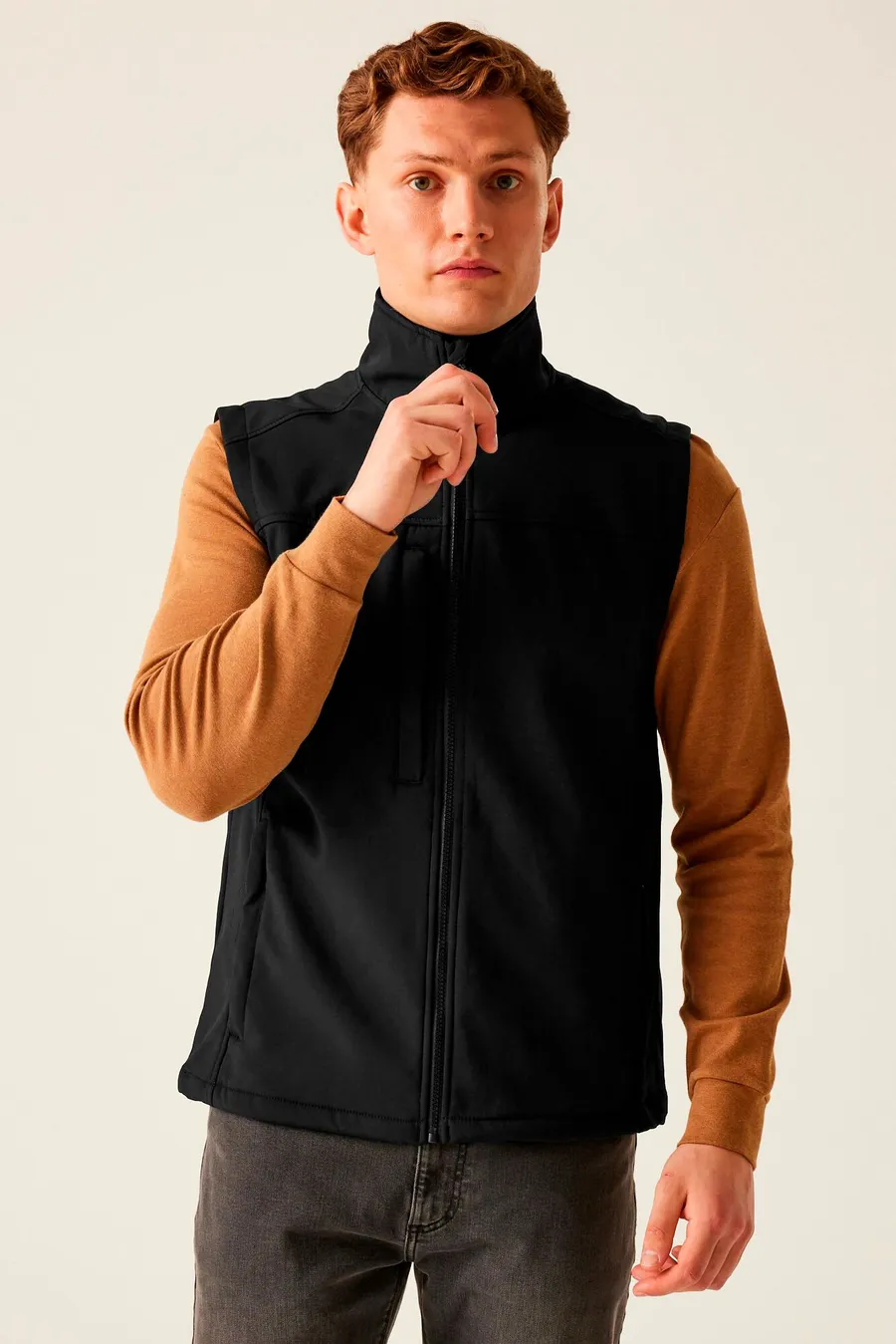 Musta hihaton softshell-liivi päällä, korkea kaulus ja koko pituudelta vetoketju.