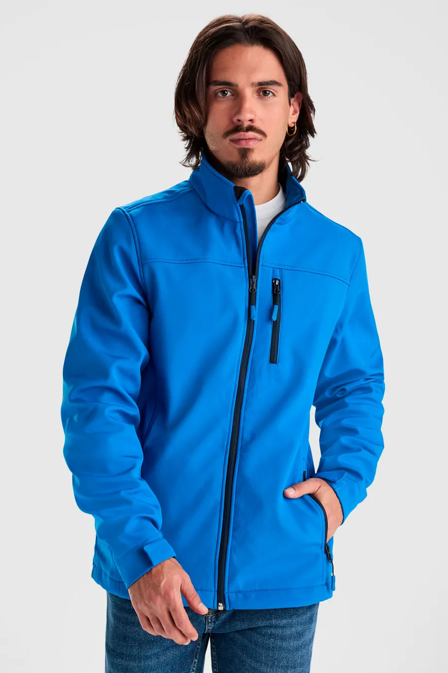 Kirkkaansininen Antartida softshell-takki pystykauluksella ja vetoketjullisella rintataskulla.