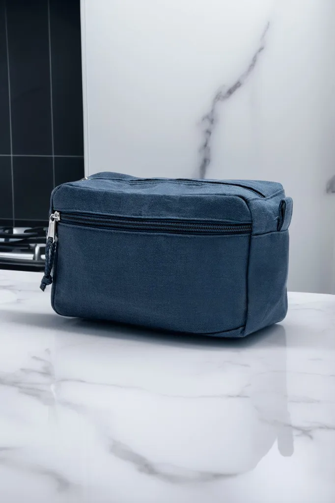 Sininen Prado-toilettilaukku vetoketjulla ja etutaskulla marmoritasolla.