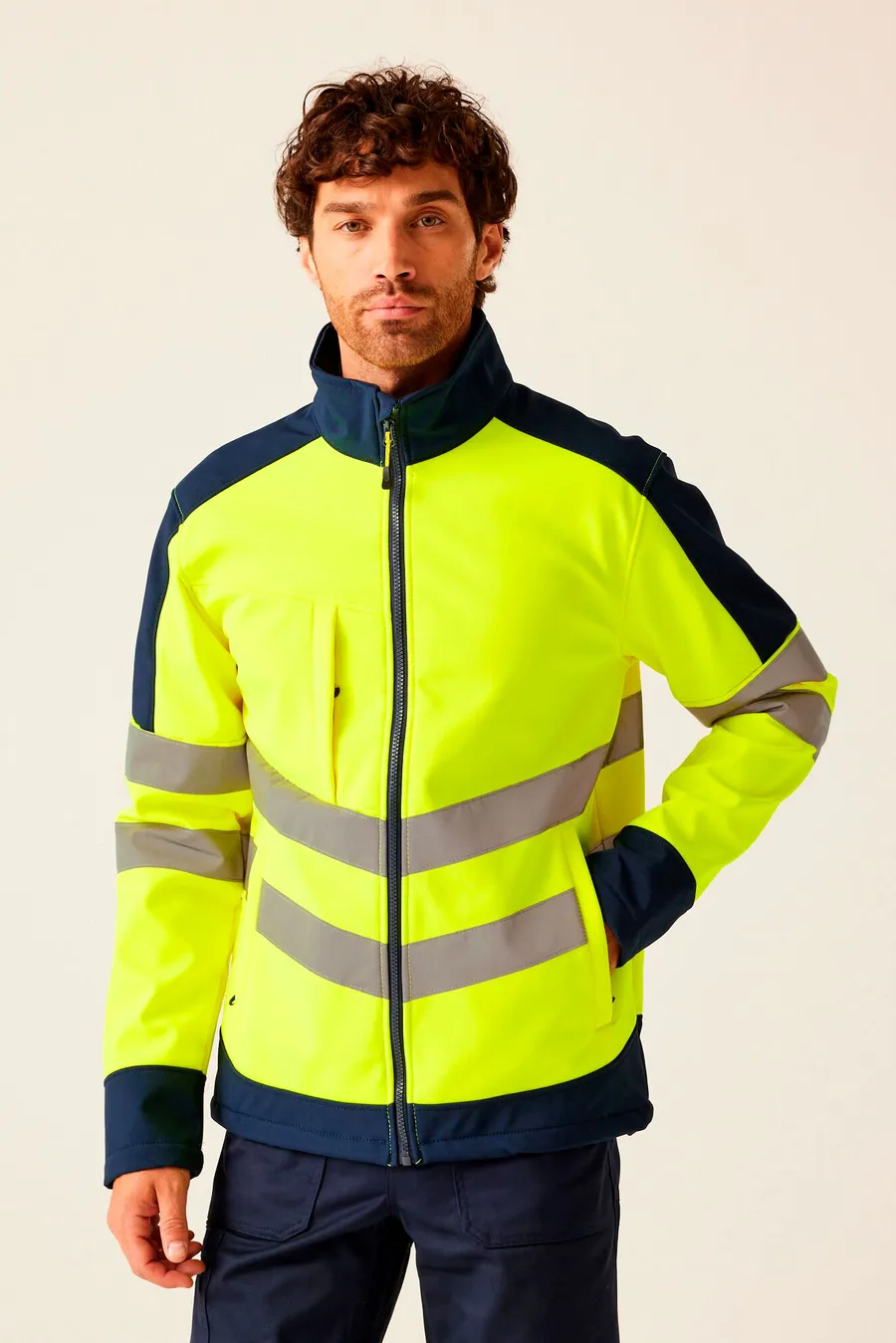 Keltainen ja tummansininen huomiovärinen softshell-takki, jossa heijastavat raidat vartalolla ja hihoissa.