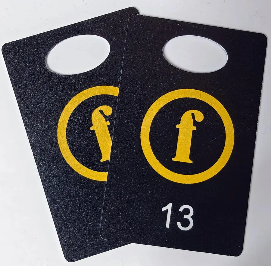 Black cloakroom tags with a yellow print and white number 13.