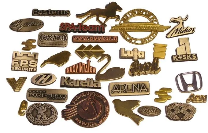 Gold- and bronze-toned metal pin badges with various company and organisation logos and text.