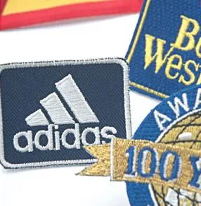 Embroidered fabric badges: navy Adidas logo and round gold-white Best Western badge.